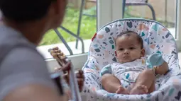 Fedi Nuril bermain gitar saat menidurkan anaknya Aksa. Dikenal sebagai sosok yang family man banget, tentunya Fedi Nuril sangat telaten dalam asuh buah hati. (Instagram/fedinuril)