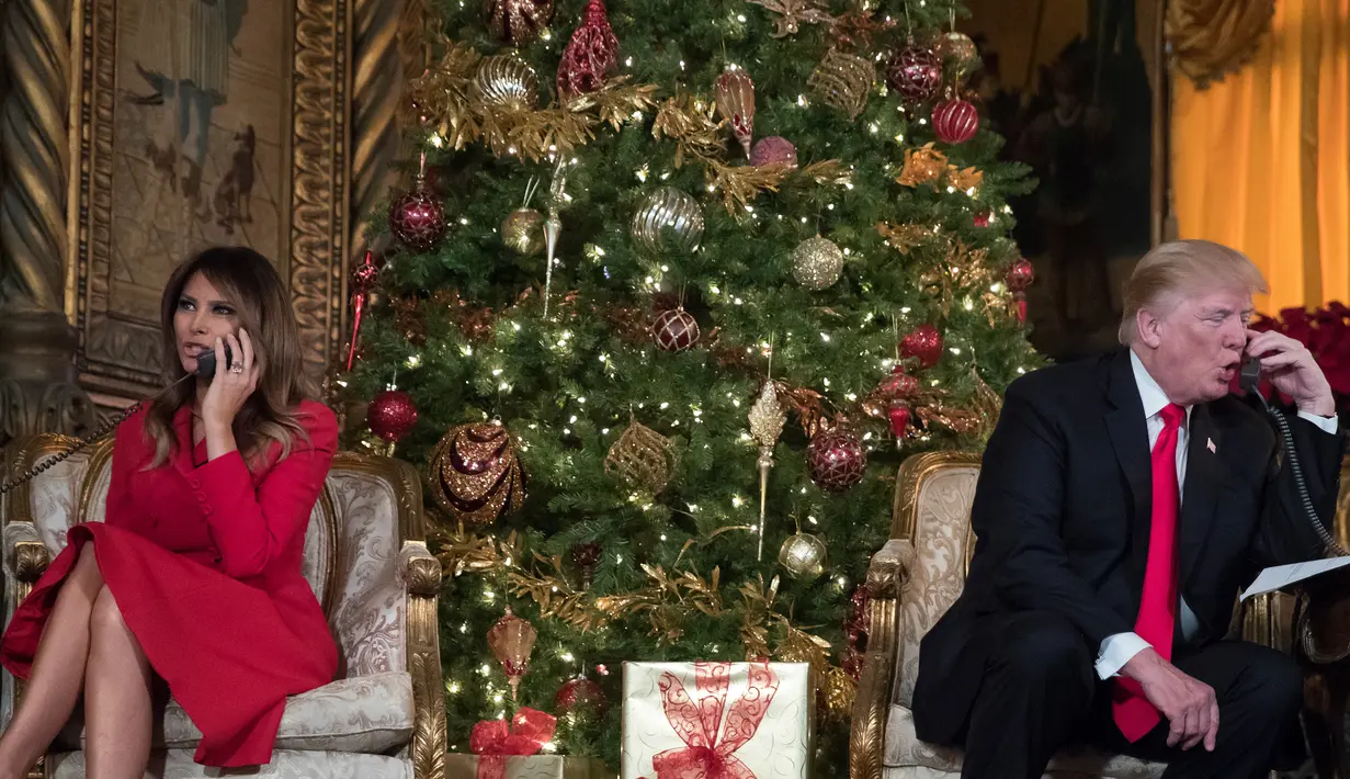 Presiden AS Donald Trump dan Melania Trump saat berbicara dengan anak-anak di telepon di Palm Beach, AS (24/12). Acara ini dibuat untuk menjelaskan keberadaan Sinterklas kepada anak-anak dan mendengarkan permintaan mereka. (AP Photo/Carolyn Kaster)