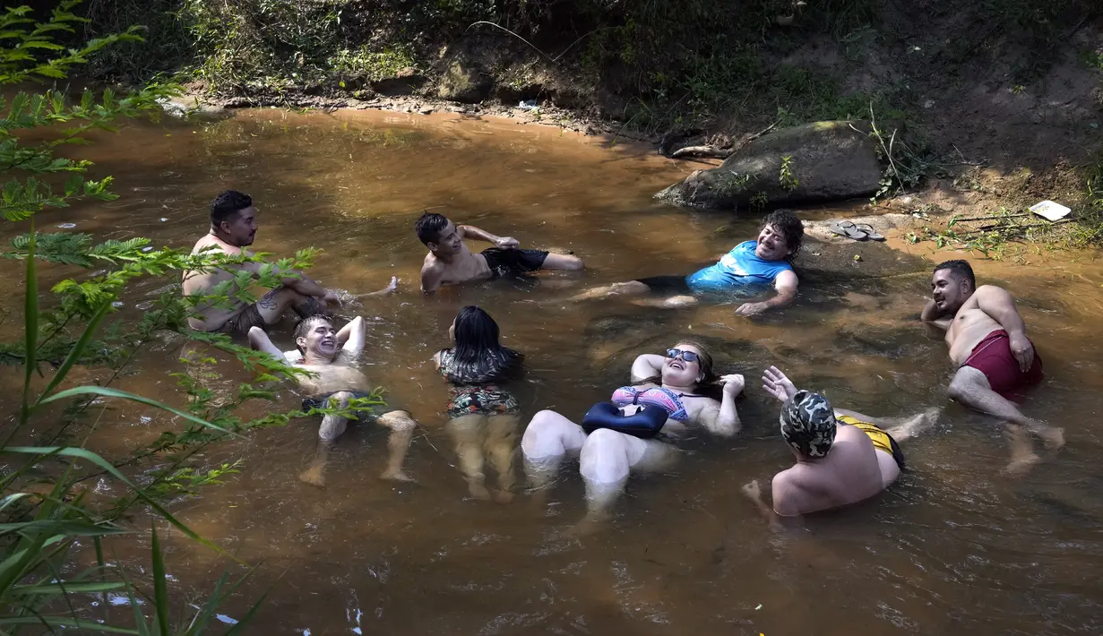 Orang-orang menyejukkan diri dari cuaca yang sangat terik di sungai saat gelombang panas di Paraguari, Paraguay, Minggu (16/1/2022). Suhu Paraguay secara umum mencapai 41 derajat celsius. (AP Photo/Jorge Saenz)