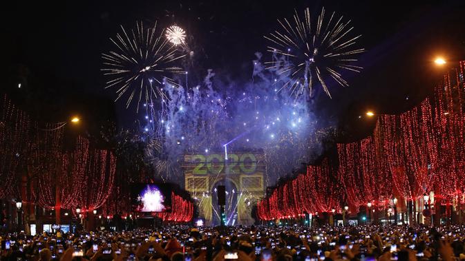 Sejumlah warga memotret kembang api di atas Arc de Triomphe ketika mereka merayakan Tahun Baru di Champs Elysees, di Paris, Prancis, Rabu (1/1/2019). (AP Photo / Christophe Ena)