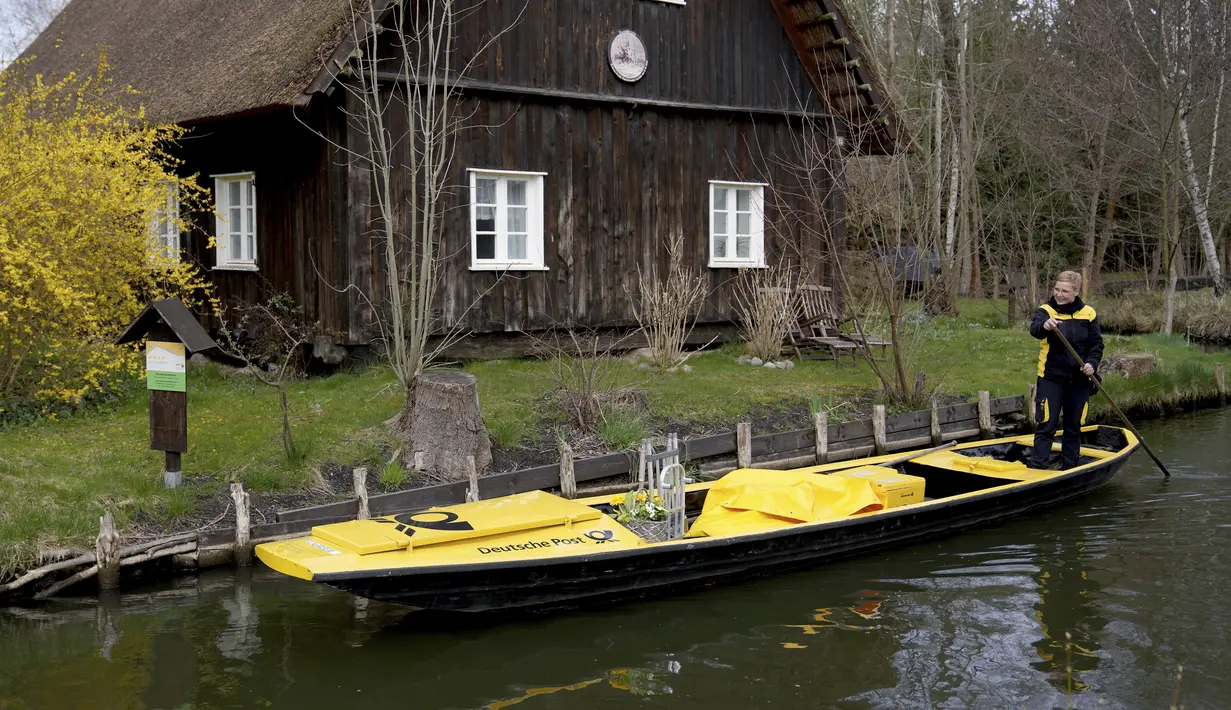 Perempuan pengirim surat Andrea Bunar mengantarkan surat dengan perahu di desa Spreewald di Luebbenau dekat Berlin, Jerman, Selasa (5/4/2022). Spreewald terletak sekitar 100 km tenggara ibukota Jerman, Berlin. (AP Photo/Michael Sohn)