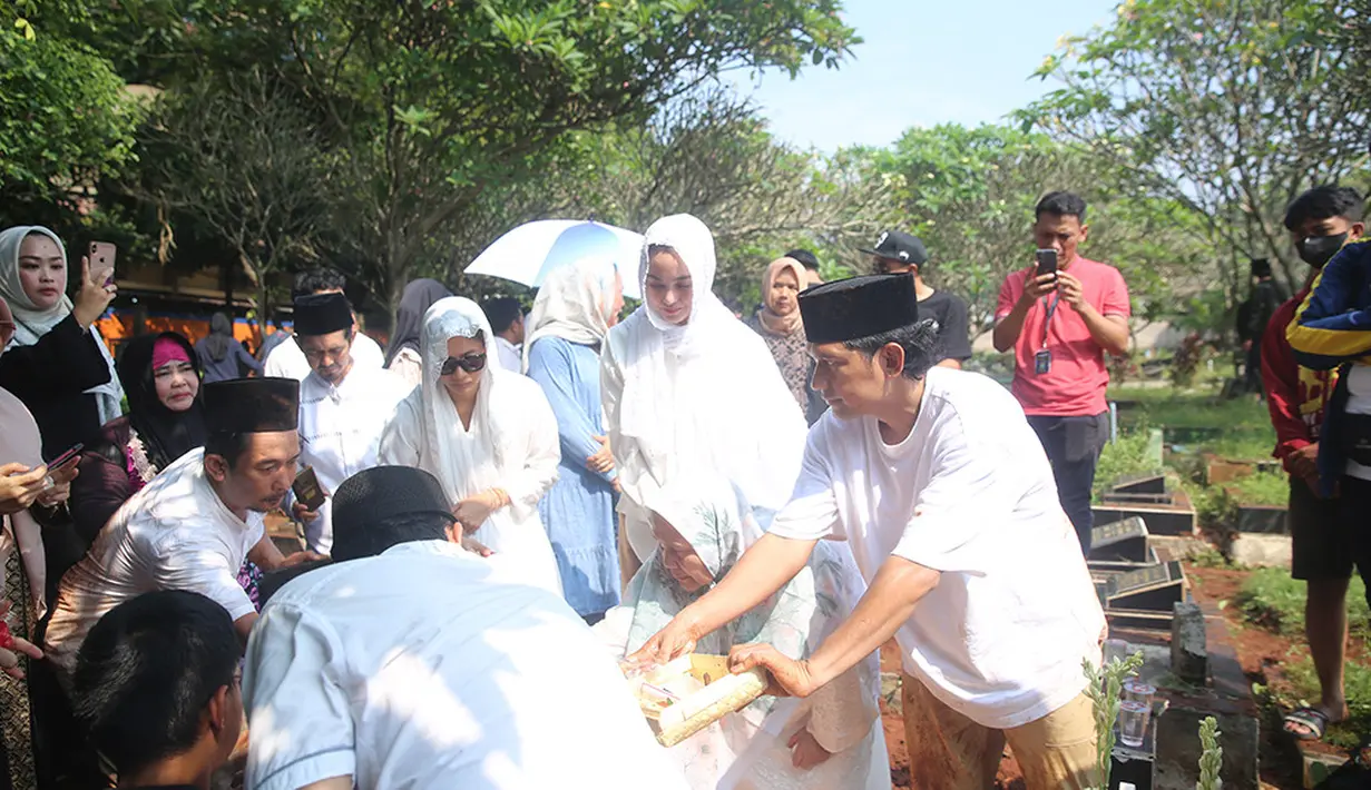 Ririn bersama suami, ibu mertua dan keluarga tampak tabur bunga di atas pusara H. Syaipudin. Ririn mengenakan pakaian dan kerudung warna putih. [Foto; Adrian Putra/Fimela.com]