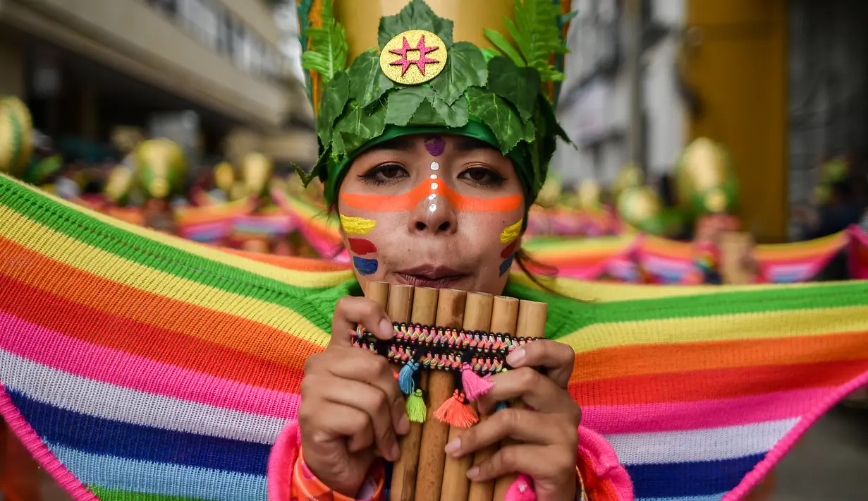 Peserta mengenakan kostum dan riasan memaikan alat musik tiup saat parade Canto a la Tierra di Pasto, Kolombia (3/1). Parade ini terdiri dari perpaduan budaya Andes, Amazon dan Pasifik. (AFP Photo/Luis Robayo)