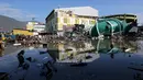 Orang-orang memeriksa kerusakan sebuah pusat perbelanjaan setelah gempa bumi dan tsunami menghantam Kota Palu di Sulawesi Tengah, Minggu (30/9). Dampak dari bencana tersebut melulunlantakkan bangunan dan ratusan jiwa meninggal dunia. (AP/Tatan Syuflana)