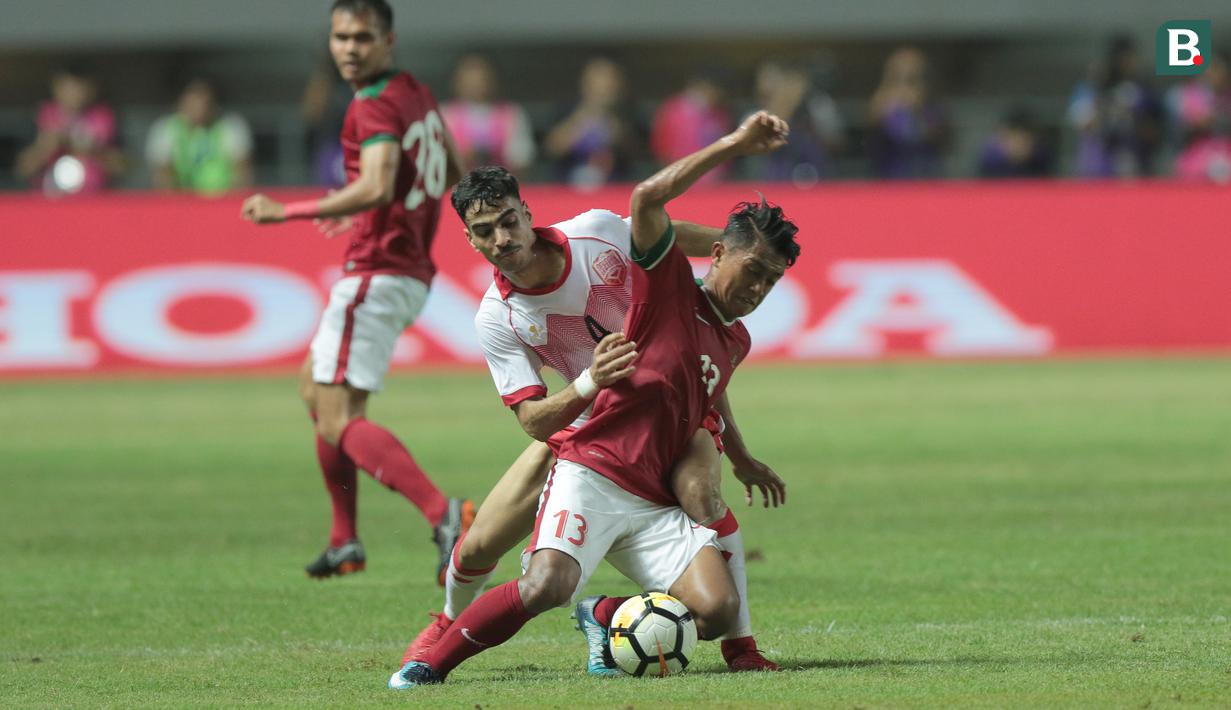 Pemain Timnas Indonesia U-23, Febri Haryadi (kanan) mencoba melewati adangan pemain Bahrain pada laga PSSI Anniversary Cup 2018 di Stadion Pakansari, Bogor, (26/4/2018). Bahrain unggul sementara 1-0. (Bola.com/Nick Hanoatubun)
