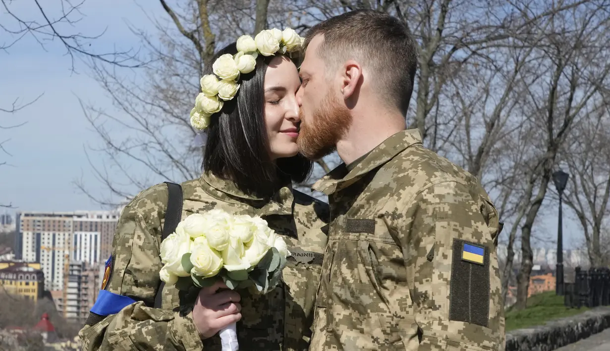 Tentara Ukraina Anastasia dan Vyacheslav berbagi momen mesra sebelum upacara pernikahan mereka di sebuah taman kota di Kiev, Ukraina, 7 April 2022. (AP Photo/Efrem Lukatsky)