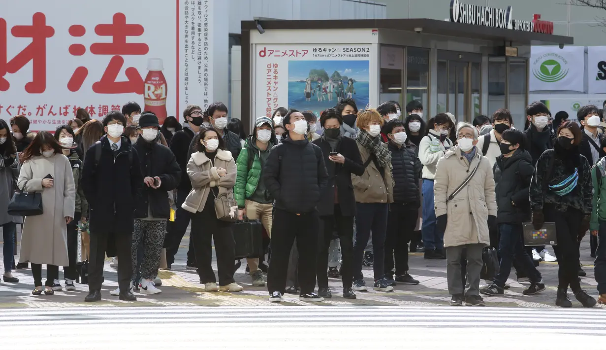 Orang-orang memakai masker untuk melindungi dari penyebaran virus corona menunggu di persimpangan di Tokyo (8/2/2021).  Jumlah infeksi virus corona di Ibu Kota Tokyo, Jepang, meningkat sampai sembilan kali lipat sejak akhir musim panas lalu. (AP Photo/Eugene Hoshiko)