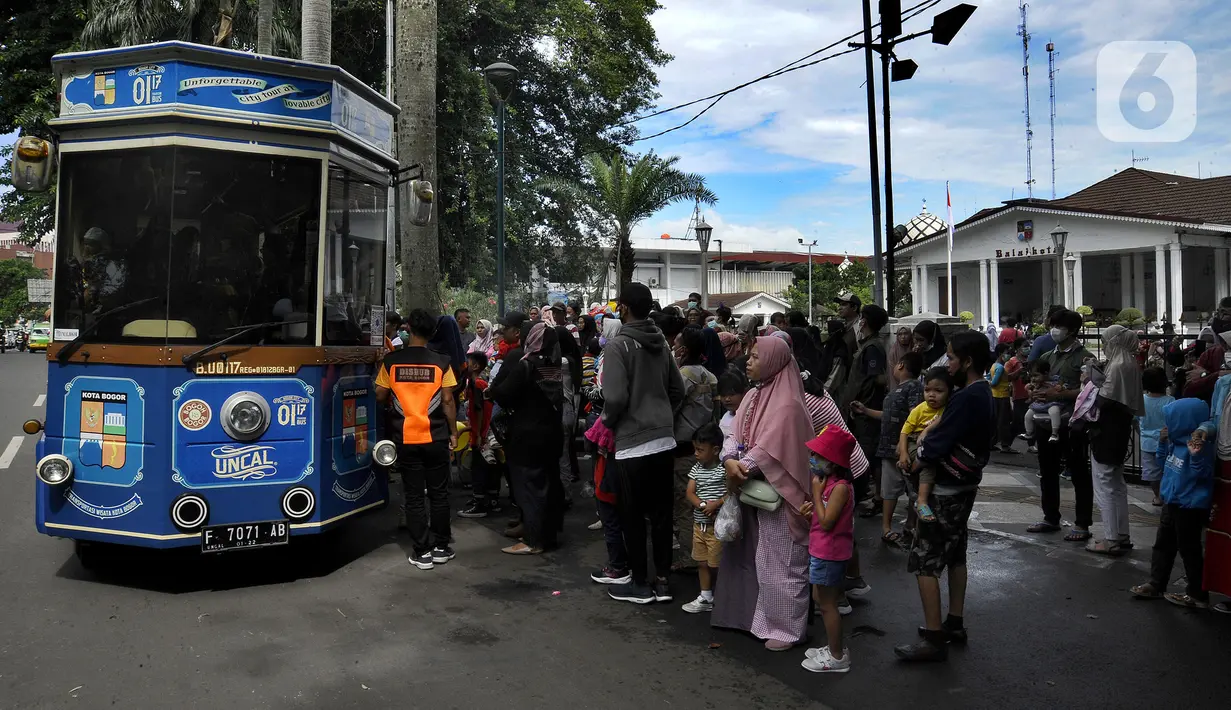 Warga antre masuk bus wisata Uncal di depan Balai Kota Bogor, Bogor, Jawa Barat, Minggu (29/5/2022). Bus wisata gratis yang disediakan untuk mengelilingi kawasan Kebun Raya Bogor setiap hari Sabtu dan Minggu ini mulai beroperasi kembali pascapandemi. (merdeka.com/Arie Basuki)