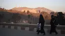 Dua wanita Afghanistan berjalan melewati Hotel Intercontinental setelah sebuah serangan di Kabul pada Senin (21/1). Kelompok bersenjata membunuh setidaknya lima orang dan melukai delapan lainnya. (SHAH MARAI/AFP)