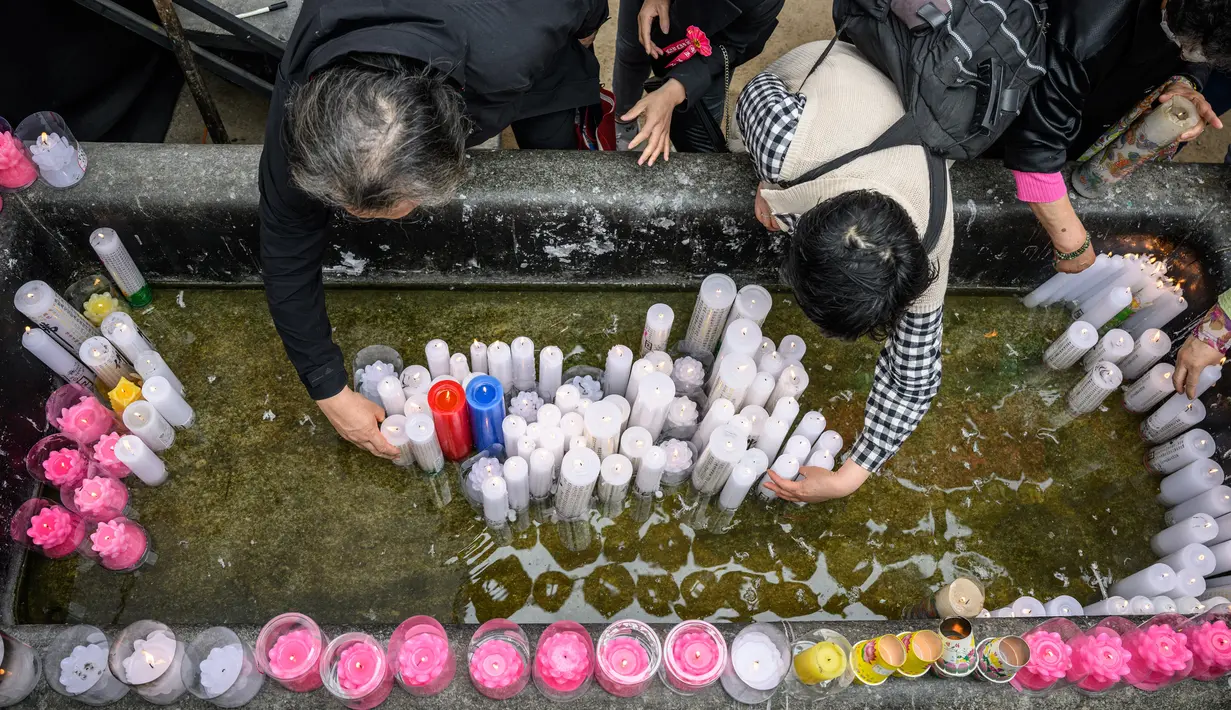 <p>Para jemaah mempersembahkan lilin setelah kebaktian untuk merayakan ulang tahun Buddha di Kuil Jogye, Seoul, Korea Selatan, Minggu (8/5/2022). (ANTHONY WALLACE/AFP)</p>