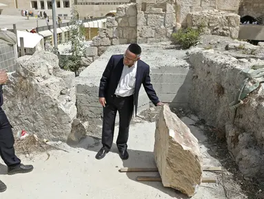 Petugas keamanan dan seorang Yahudi Ortodoks memeriksa sebuah batu besar yang jatuh dari Tembok Ratapan dua hari sebelumnya di Kota Tua Yerusalem, Rabu (25/7). Bongkahan batu itu nyaris menimpa seorang peziarah yang sedang berdoa. (AFP/AHMAD GHARABLI)