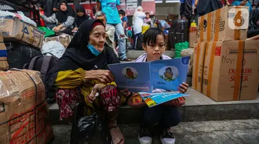 Anak-anak yang hendak ikut dalam perjalanan mudik membaca buku yang diberikan secara cuma-cuma oleh Badan Bahasa Kementerian Pendidikan, Kebudayaan, Riset, dan Teknologi (Kemendikbudristek) di Teriminal Kalideres, Jakarta, Selasa (2/4/2024). (Liputan6.com/Angga Yuniar)