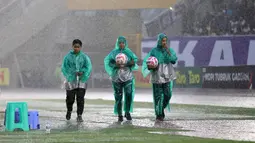 Sejumlah ball boy berjalan di bawah guyuran hujan dalam laga final Pegadaian Liga 2 2024/2025 antara Bhayangkara FC melawan PSIM Yogyakarta di Stadion Manahan, Solo, Jawa Tengah, Rabu (26/02/2025). (Bola.com/Abdul Aziz)