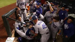 Pemain Los Angeles Dodgers, Cody Bellinger dibantu rekan-rekannya saat terjatuh di tempat istirahat pada pertandingan kelima dalam game 3 dari Divisi Liga Nasional baseball di Phoenix (9/10). (Christian Petersen / Getty Images / AFP)