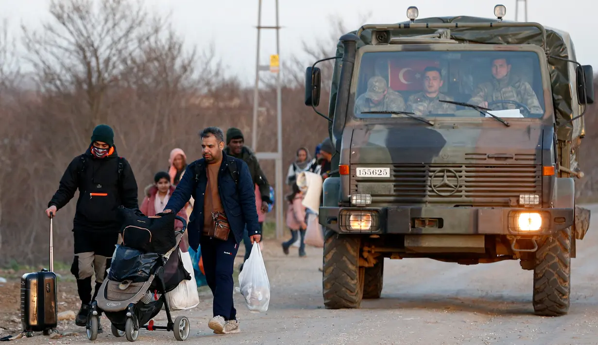 Truk militer Turki melintas saat para migran berjalan menuju perbatasan Yunani di Gerbang Pazarkule, Edirne, Turki, Selasa (3/3/2020). (AP Photo/Darko Bandic)
