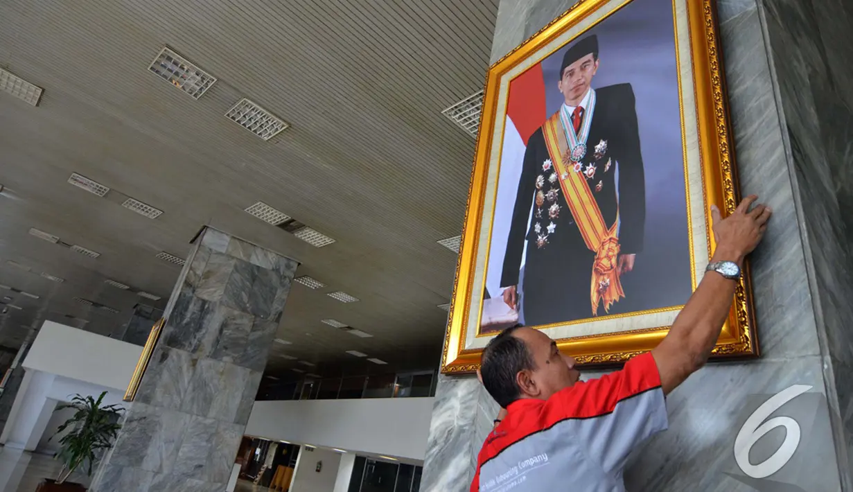 Petugas memasang foto Presiden Jokowi di pilar Gedung Nusantara III Kompleks Parlemen Senayan, Selasa (23/12/2014). (Liputan6.com/Andrian M Tunay)