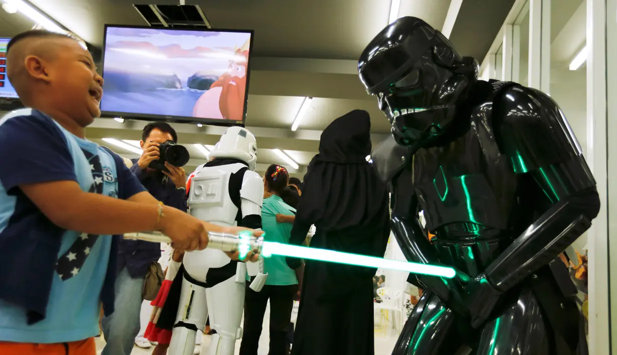 Anggota klub penggemar Star Wars Thailand dengan kostum Shadow stormtrooper bermain bersama seorang anak selama perayaan Star Wars Day di Queen Sirikit National Institute of Child Health, Bangkok, Rabu (4/5). (REUTERS/Chaiwat Subprasom)