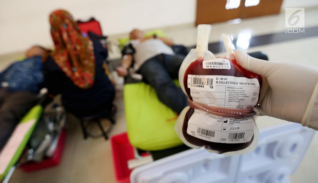 Petugas Palang Merah Indonesia (PMI) menunjukan darah yang sudah dimasukan ke Jakarta, Minggu (3/12). Kegiatan donor darah tersebut diadakan dalam rangkaian acara Natal. (Liputan6.com/JohanTallo)