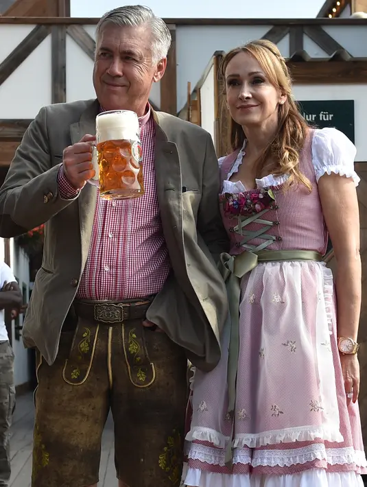 Pelatih Bayern Munchen, Carlo Ancelotti ditemani istrinya, Mariann Barrena McClay memegang cangkir bir saat mereka berpose selama festival bir Oktoberfest 2017 di Munich, Jerman (23/9). (AFP Photo/Christof Stache)