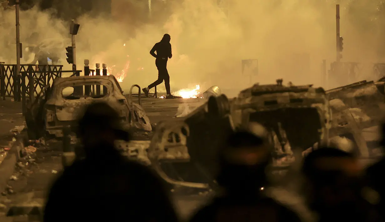 <p>Seorang demonstran berlarian pada malam ketiga protes yang dipicu oleh penembakan fatal polisi terhadap seorang pengemudi berusia 17 tahun di Nanterre, Prancis, Jumat (30/6/2023). (AP Photo/Aurelien Morissard)</p>