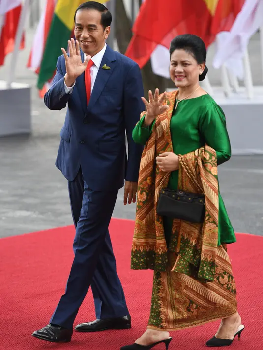 Presiden RI, Joko Widodo didamping Ibu Negara Iriana Widodo menyapa awak media saat tiba menghadiri KTT G20 di Hamburg, Jerman, (7/7). Sejumlah pemimpin negara berkumpul dalam KTT G20 pada 7-8 Juli 2017. (AFP Photo/Patrik Stollarz)