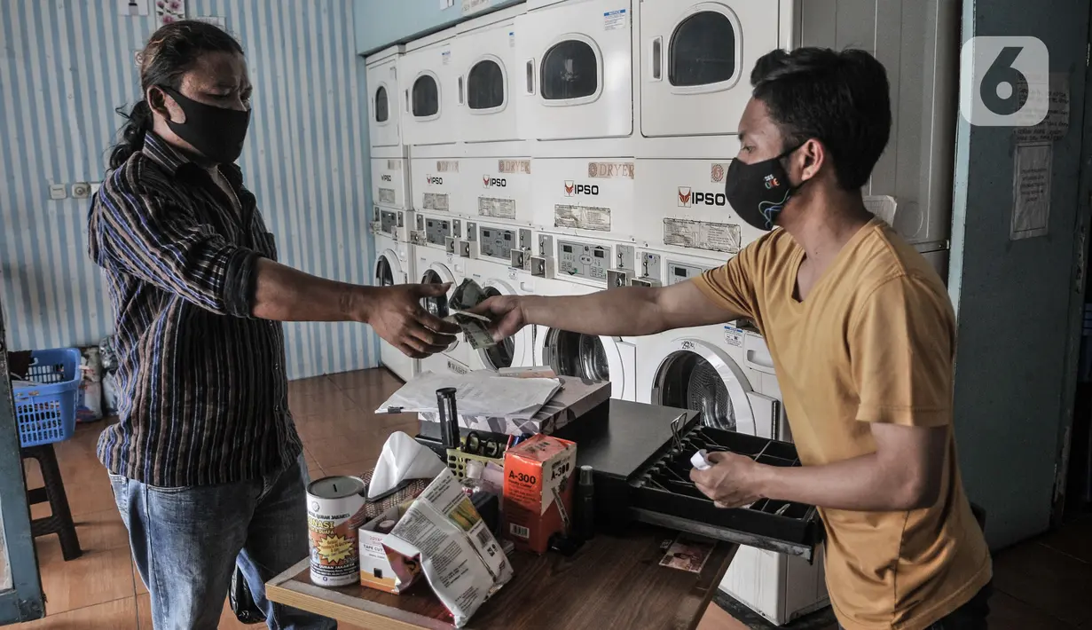 Pekerja melayani pelanggan cuci pakaian mandiri di Jaksa Clean Coin Laundry, Jalan Jaksa, Jakarta, Kamis (1/4/2021). Seorang pekerja mengungkapkan sebelum pandemi biasanya menerima rata-rata 10 pelanggan dalam sehari, namun kini merosot menjadi 4 pelanggan per hari. (merdeka.com/Iqbal S Nugroho)