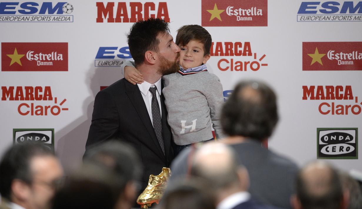 Lionel Messi mencium anaknya Thiago usai menerima penghargaan sepatu emas Europa pada Golden Shoe awards 2017 di Antigua Fabrica Estrella Damm, Barcelona, (24/11/2017). (AFP/Josep Lago)