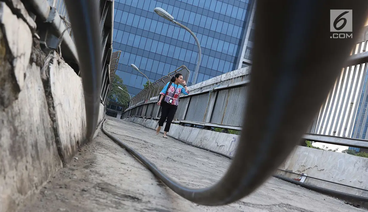 Pejalan kaki melintasi jembatan penyeberangan orang tanpa atap dan tidak terawat di Jalan TB Simatupang, Jakarta, Rabu (10/10). Kondisi tersebut menyebabkan JPO terkesan kumuh serta mengurangi kenyamanan pejalan kaki. (Liputan6.com/Immanuel Antonius)