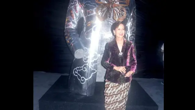 Seorang wanita berfoto dengan skulptur kebaya karya Sri Astari Rasjid.