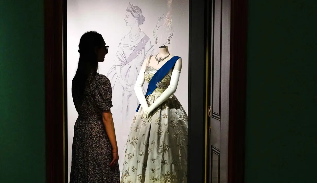 Seorang anggota staf Royal Collection Trust melihat pajangan yang menampilkan busana yang dikenakan Putri Elizabeth untuk Jamuan Kenegaraan di Gedung Putih yang diberikan oleh Presiden Dwight Eisenhower pada tahun 1957, yang dipamerkan dalam pameran 'Queen Elizabeth II: Her Life in Style', di The King's Gallery, Istana Buckingham, London, Inggris, Kamis 9 April 2026. (AP Photo/Kirsty Wigglesworth)