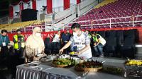 Ketua INASPOC, Gibran Rakabuming Raka sedang memotong tumpeng dalam acara wilujengan atau selamatan jelang upacara pembukaan ASEAN Para Games 2022, Kamis malam (28/7).(Liputan6.com/Fajar Abrori)
