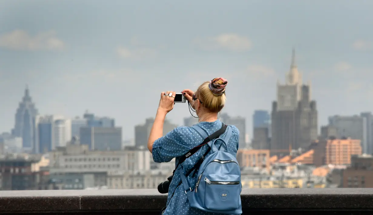 Seorang wanita mengabadikan Pusat Bisnis Internasional Moskwa (Moskva) City) di bukit Vorobyovy, Rusia (12/7). Bukit ini memiliki ketinggian mencapai 220 meter di atas permukaan laut. (AFP Photo/Alexander Nemenov)