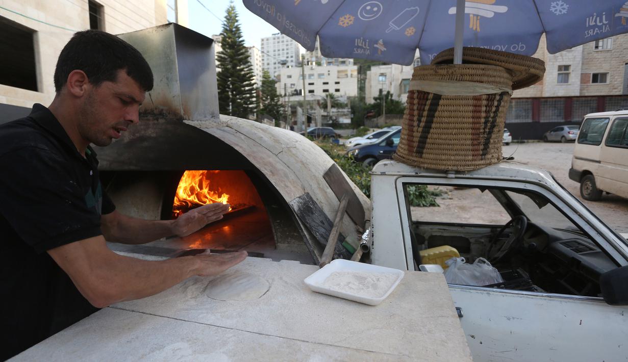 Penjual roti Palestina Mohammed Abu Saud menyiapkan roti di Kota Nablus, Tepi Barat, (3/5/2020). Abu Saud menjual roti keliling untuk membantu warga mendapatkan roti ketika mereka berada di rumah. (Xinhua/Ayman Nobani)
