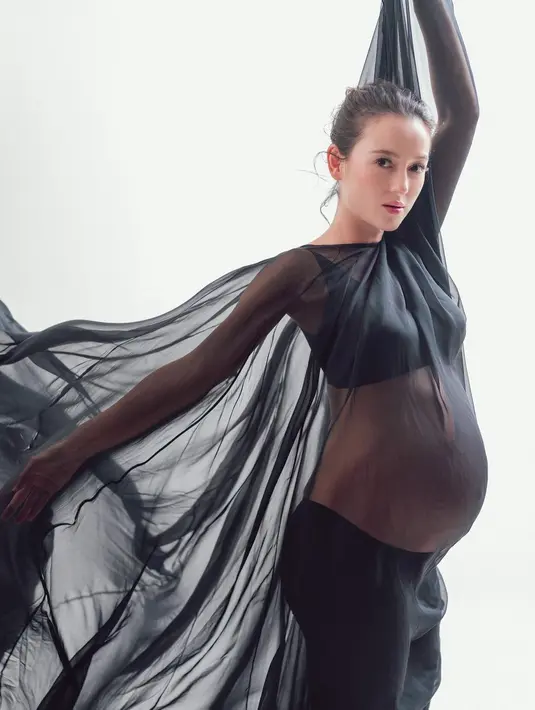 Gaun transparan melengkapi penampilannya yang membuat penampilan maternity shoot-nya makin keren.
 [Instagram/julstelle]