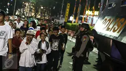 Warga yang sedang takbiran melintas didepan petugas Brimob yang berjaga-jaga dikawasan Bunderan HI, Jakarta, Selasa (6/7). (Liputan6.com/Faizal Fanani)