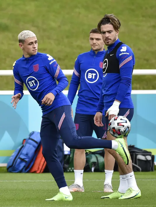 Pemain Inggris Jack Grealish (kanan) menyaksikan Phil Foden mengontrol bola saat sesi latihan di St George's Park, Burton upon Trent, Inggris, Senin (5/7/2021). Inggris akan melawan Denmark pada pertandingan semifinal Euro 2020. (AP Photo/Rui Vieira)