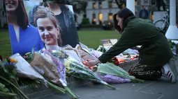 Seorang wanita meletakkan bunga di dekat foto anggota parlemen Inggris, Jo Cox di alun-alun Parlemen, London, Kamis (16/6). Meski sudah dilarikan ke rumah sakit, nyawa Jo Cox tak tertolong dan dinyatakan tewas sejam kemudian. (Daniel Leal-Olivas/AFP)