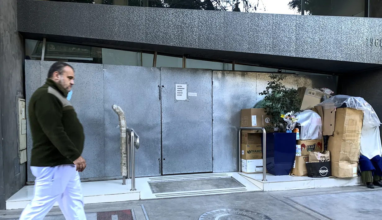 Seorang tunawisma terihat berada di luar hotel yang ditutup di Buenos Aires, Argentina pada 22 Juni 2021. Pembatasan akibat pandemi corona Covid-19 telah menyebabkan penurunan jumlah wisatawan selama setahun di Argentina. (RONALDO SCHEMIDT / AFP)
