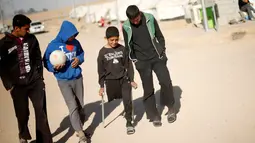 Jasim Abudllah bermain bersama teman-temannya di sekitar kamp pengungsian Debaga, Erbil, Irak (24/11). Meski hidup dengan satu kaki akibat terkena serangan udara, Jasim berusaha hidup seperti bocah normal lainya. (Reuters/Mohammed Salem)