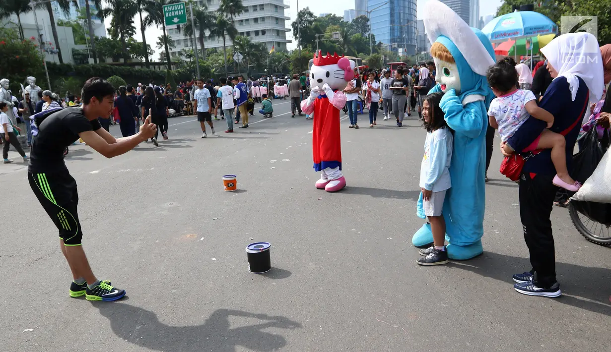 Warga sedang foto dengan seniman berkostum boneka Masha saat kegiatan Car Free Day di Bundaran HI di Jakarta, Minggu, (12/11). Warga merasa terhibur dengan adanya seniman berkostum ini. (Liputan6.com/Fery Pradolo)