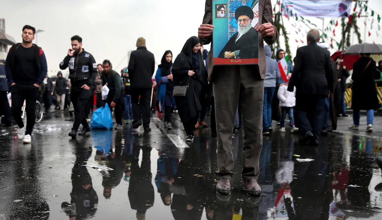 Seorang pria memegang poster bergambar Pemimpin Tertinggi Iran Ayatollah Ali Khamenei dalam upacara peringatan 40 tahun Revolusi Islam Iran di Teheran, Senin (11/2). (AP Photo/Ebrahim Noroozi)