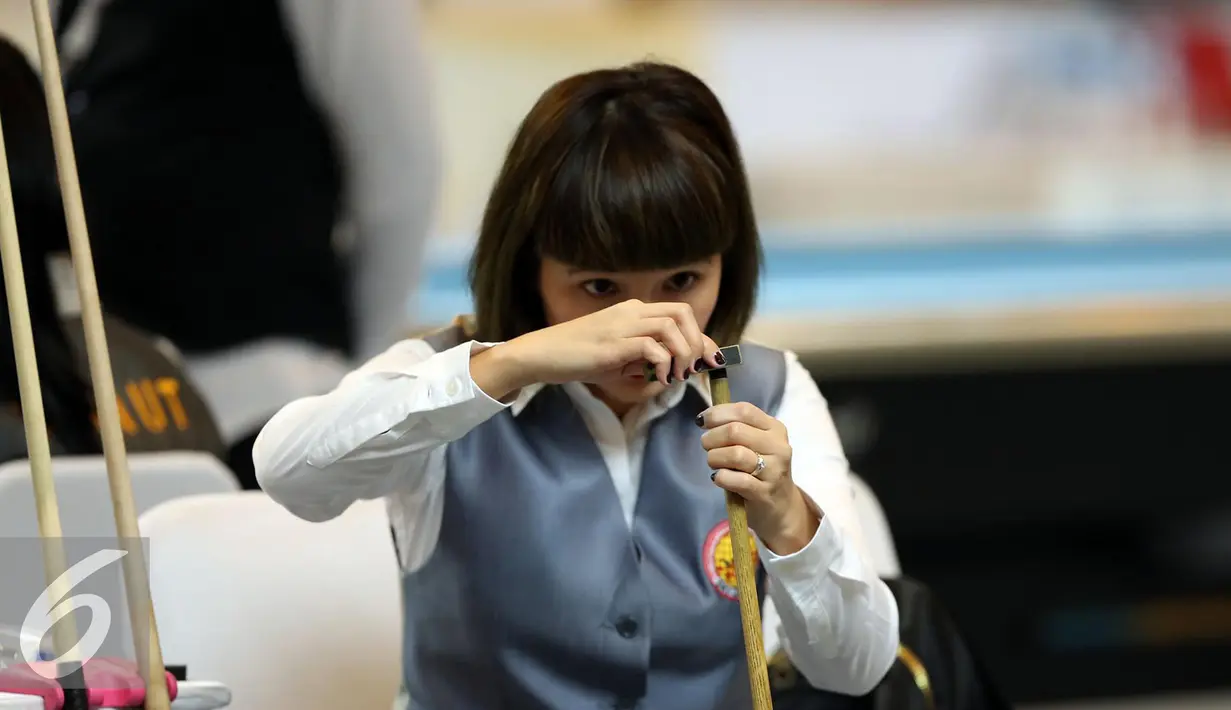 Pebiliar putri DKI Jakarta, Angeline M Ticoalu menggosok stik saat laga penyisihan 10 ball PON XIX Jabar di Graha Manggala Siliwangi, Bandung, Kamis (22/9). Angeline berhasil mengalahkan pebiliar Papua, Ari S Wati. (Liputan6.com/Helmi Fithriansyah)
