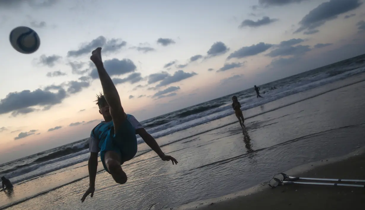 Pemuda Palestina Mohammed Eliwa menendang bola saat bermain di pantai di Kota Gaza (20/9/2019). Eliwa 17 tahun dan Ahmed al-Khoudari 20 tahun kehilangan satu kakinya saat bentrok di perbatasan Israel. (AFP Photo/Mahmud Hams)