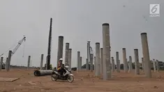 Pekerja melintas di depan tiang pancang proyek Stadion BMW, Jakarta, Rabu (10/7/2019). Di tengah kasus sengketa lahan dengan PT Buana Permata Hijau, PT Jakarta Propertindo (Jakpro) tetap melanjutkan pembangunan Stadion BMW. (merdeka.com/Iqbal S. Nugroho)