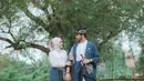 Kompak memakai baju adat nuansa biru, mereka tampak ceria berpose di tengah pemandangan alam. Keduanya tampak bergandengan dan saling menatap, romantis banget.(Liputan6.com/IG/@aryanifitriana24)