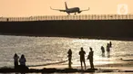 Wisatawan mengunjungi objek wisata Pantai Kelan dengan latar belakang pesawat yang mendarat di Tuban, Badung, Denpasar, Kamis (5/5/20222). Kunjungan wisatawan domestik (Wisdom) ke Pulau Bali, saat libur Lebaran Idul Fitri tahun 2022 terus meningkat. Per hari kedatangan wisdom rata-rata 40 ribu. (merdeka.com/Arie Basuki)