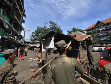 Sejumlah petugas satpol PP membongkar bangunan liar di kawasan rusun tanah tinggi, Jakarta, Rabu (4/3/2015).  Sebanyak 10 bangunan liar di Rumah Susun (Rusun) Tanah Tinggi ditertibkan aparat satpol PP. (Liputan6.com/Faizal Fanani)