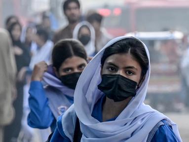 Para siswi sekolah yang mengenakan masker tiba di sebuah sekolah di tengah kondisi kabut asap di Lahore pada Senin 4 November 2024. (Arif ALI/AFP)