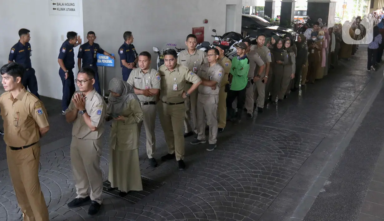 Para ASN berjejer di halaman Balai Kota DKI Jakarta antre untuk bertemu Penjabat (Pj) Gubernur DKI Jakarta Heru Budi Hartono saat Halal bihalal di hari pertama masuk kerja pascalibur Lebaran Idul Fitri 1445 H. (Liputan6.com/Herman Zakharia)
