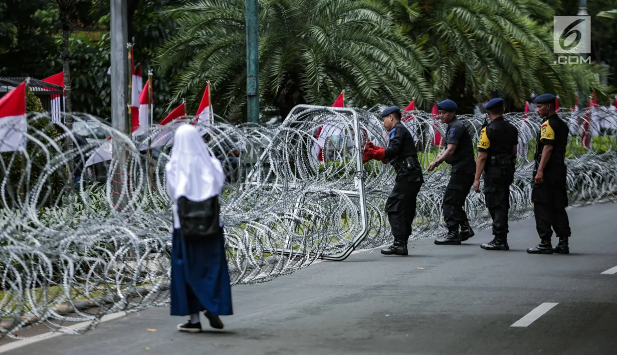 Personel Brimob memasang kawat berduri di sekitar area gedung KPU, Jakarta, Jumat (1/3). Kawat berduri itu untuk mengantisipasi massa Forum Umat Islam (FUI) dan Gerakan Jaga Indonesia yang akan menggelar aksi di depan KPU. (Liputan6.com/Faizal Fanani)